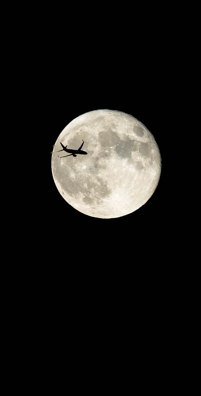 Commercial plane crossing in front of the full moon