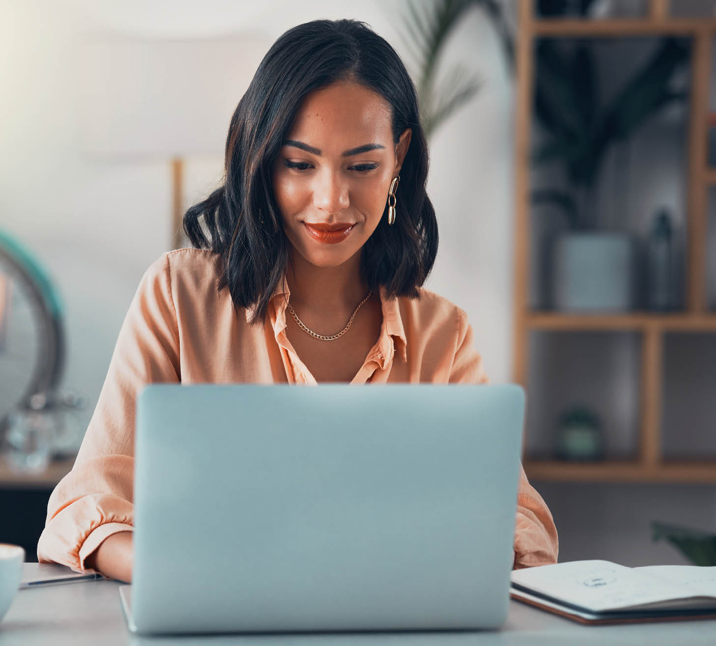 Woman working on laptop online, checking emails and planning on the internet while sitting in an office alone at work. Business woman, corporate professional or manager searching the internet